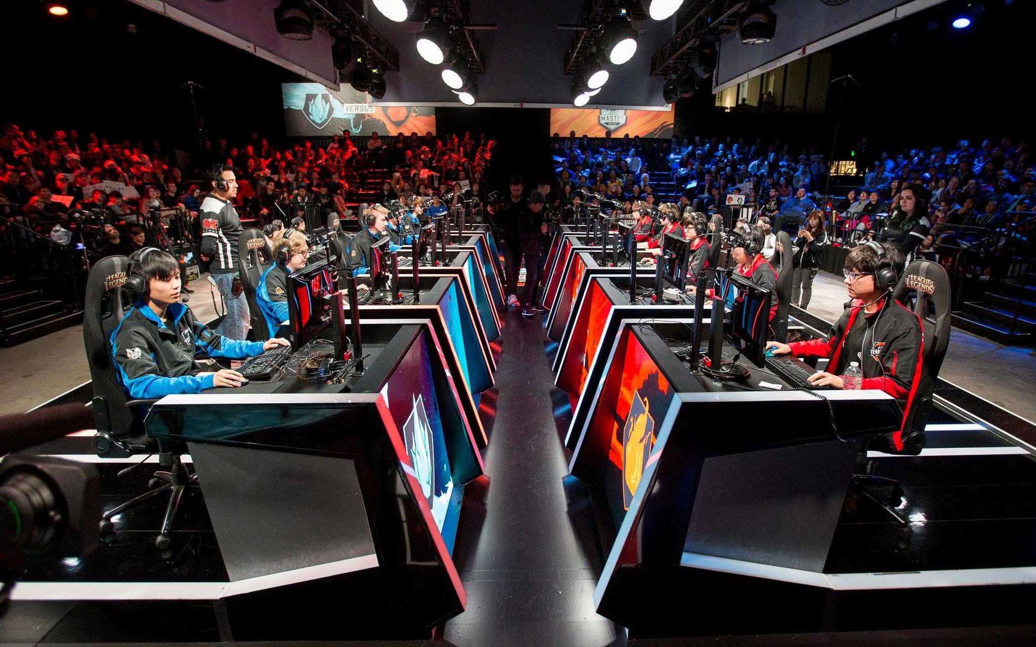 Esports-teams geconcentreerd tijdens een live competitie in een arena, met publiek op de achtergrond, klaar voor de strijd