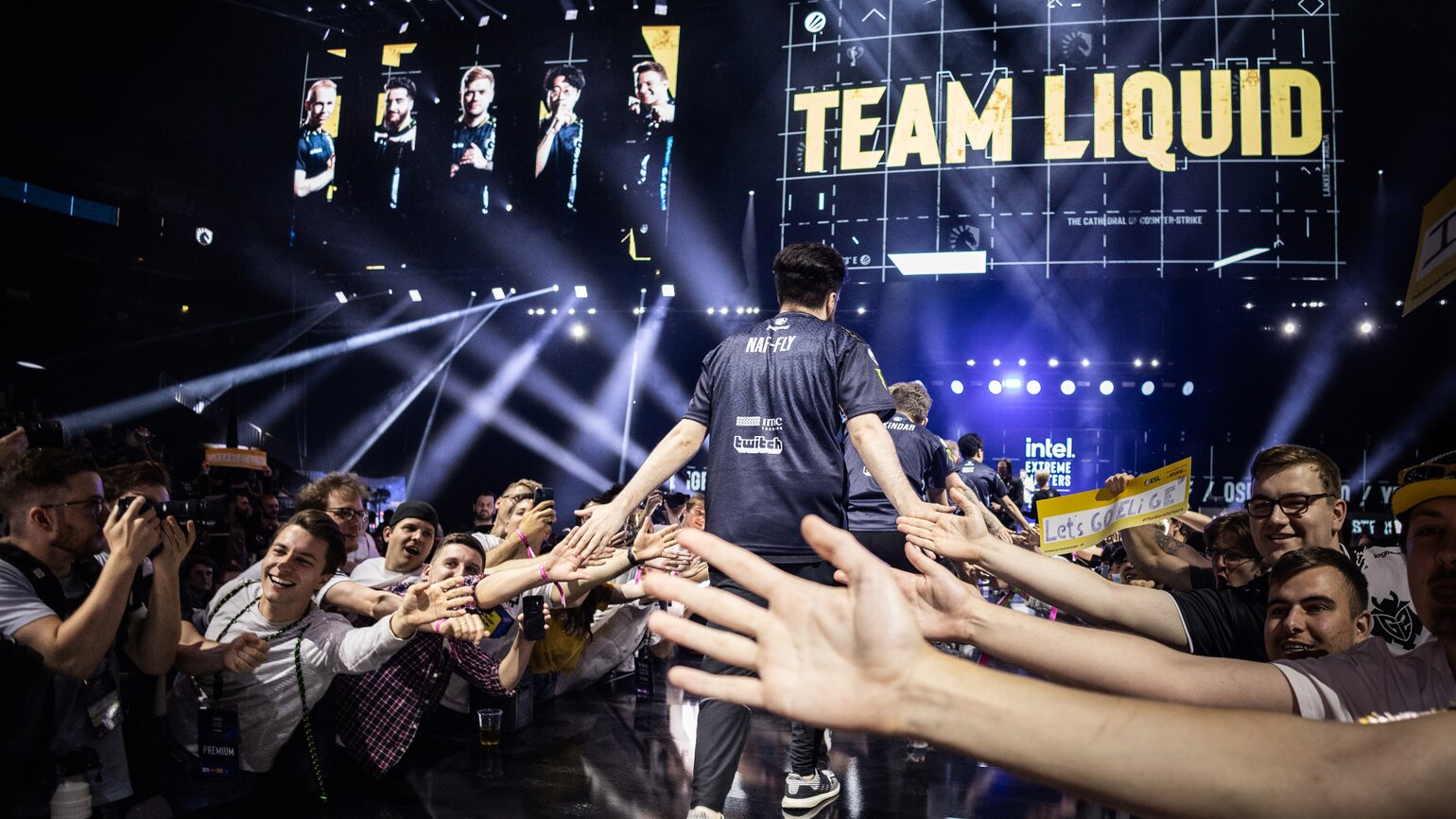 Esportspeler van Team Liquid viert overwinning met fans die handen reiken voor een high-five in een verlichte arena